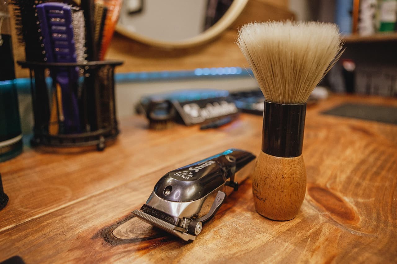 Clippers and a shaving brush on a wooden counter