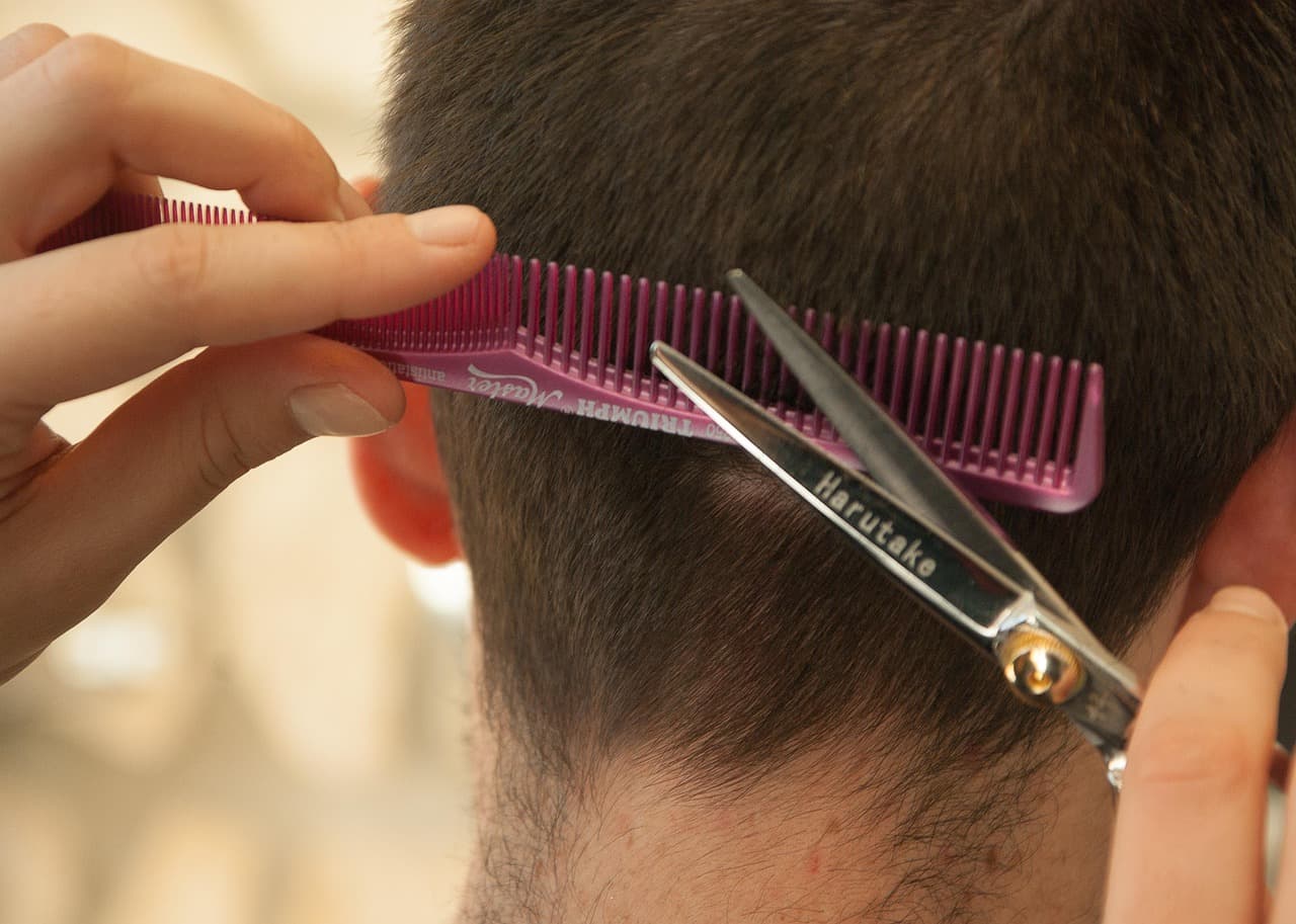 Barber cutting the back of a head with comb and scissors