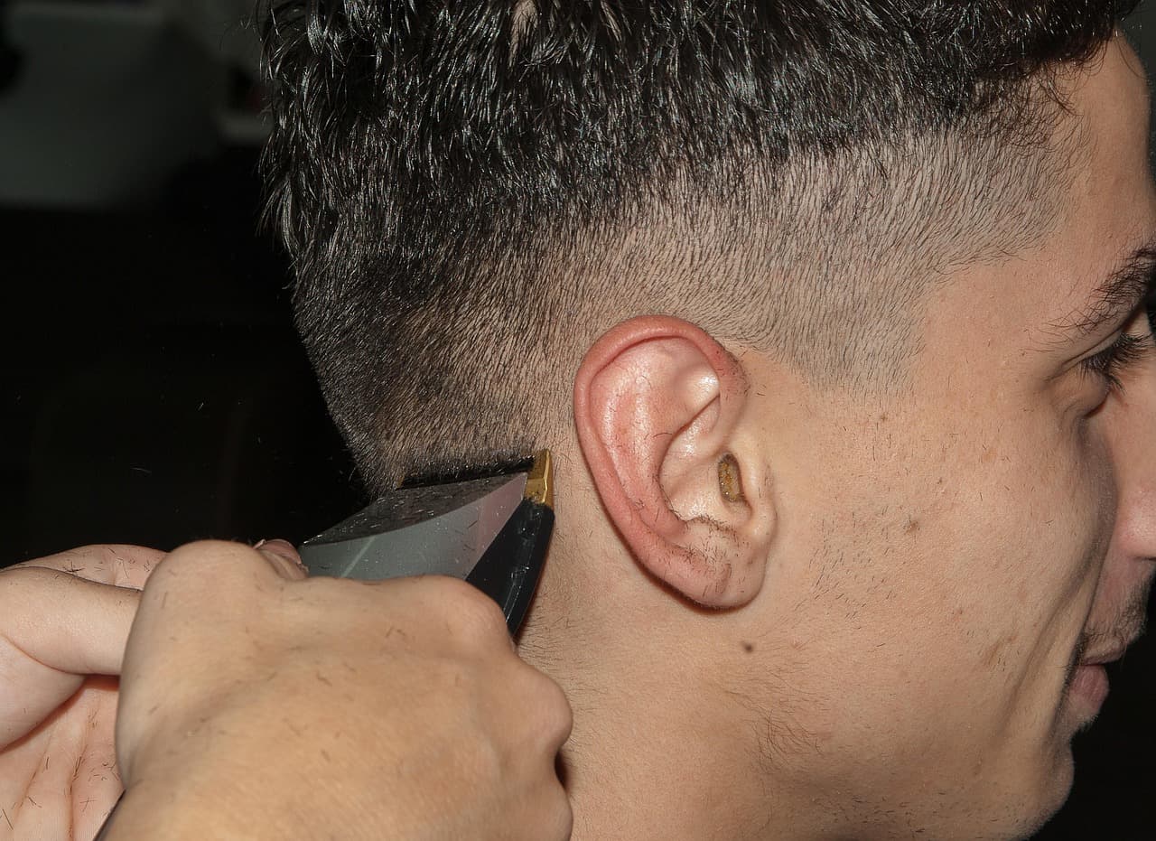 Barber tapering the hair above the ear with clippers