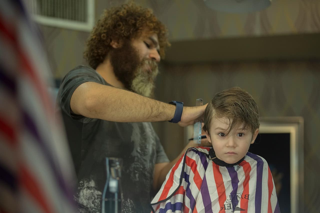 Young boy in a striped cape getting his hair cut